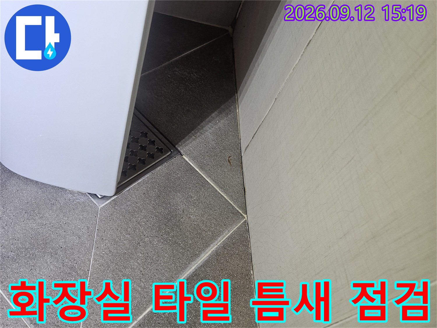 세면대 밑 배수구 주변의 타일 배열과 상태를 보여주는 사진입니다.