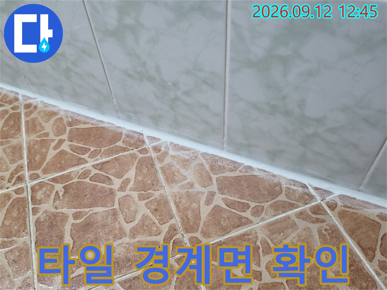 벽면 타일의 경계와 바닥 타일의 무늬가 보이는 화장실 내부입니다.
