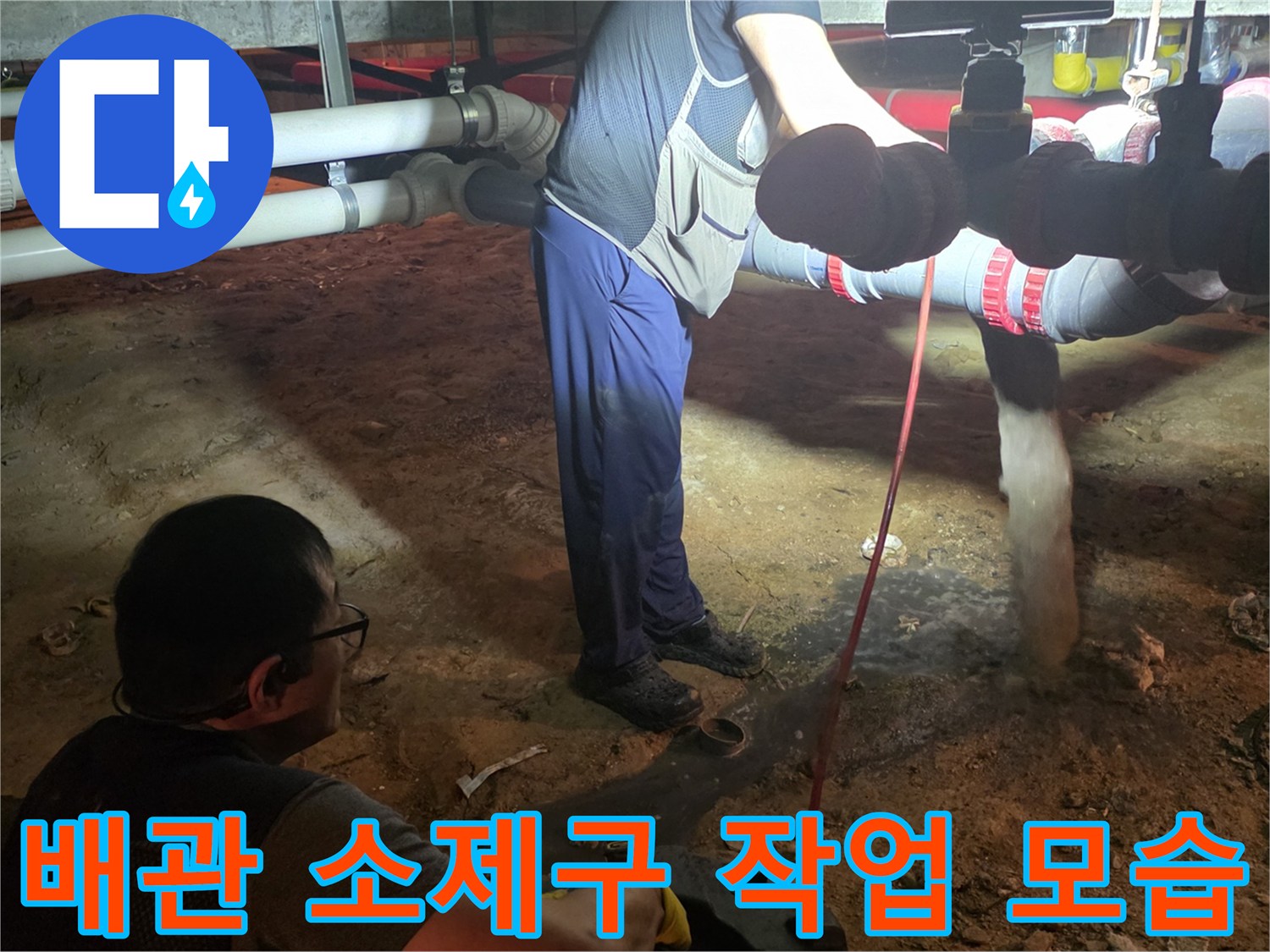 배관 막힘을 해결하기 위해 소제구를 열고 장비를 투입하는 현장 사진입니다.