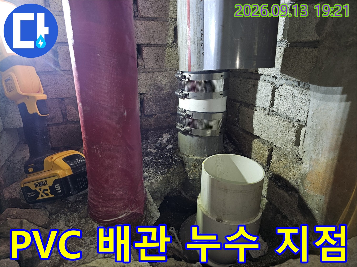 굴착된 벽면 사이로 보이는 은색 밴드 체결 부위와 PVC 파이프의 모습입니다.