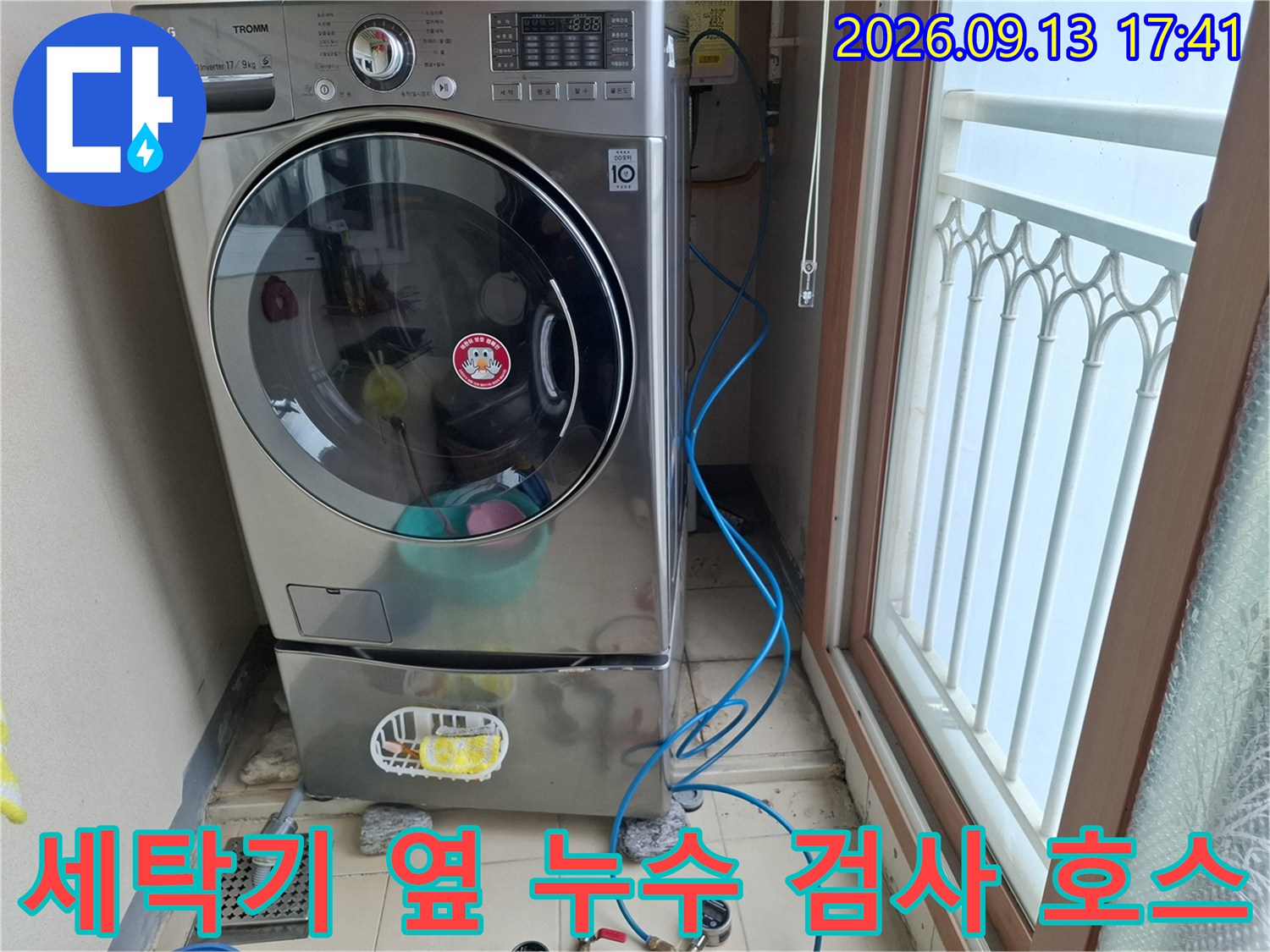 세탁실 배수구 주변에 놓인 파란색 압력 테스트용 가스 호스