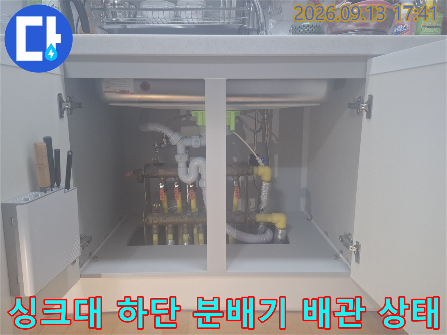 싱크대 내부의 보일러 분배기와 노란색 배관 연결 구조를 보여줍니다.
