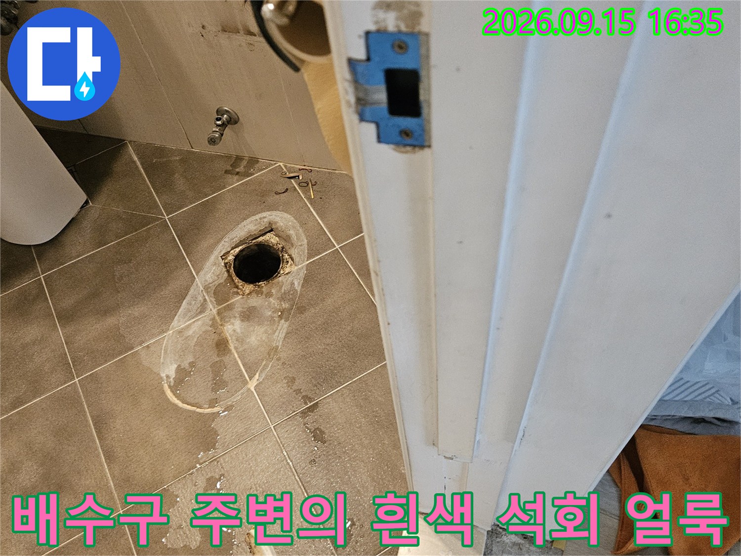 화장실 바닥 배수구 근처의 하얀 자국과 젖은 타일