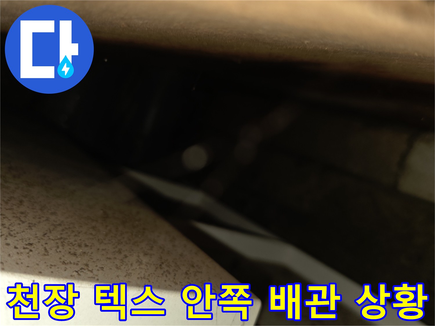 천장 내부 틈새로 보이는 젖은 콘크리트와 배관 부위