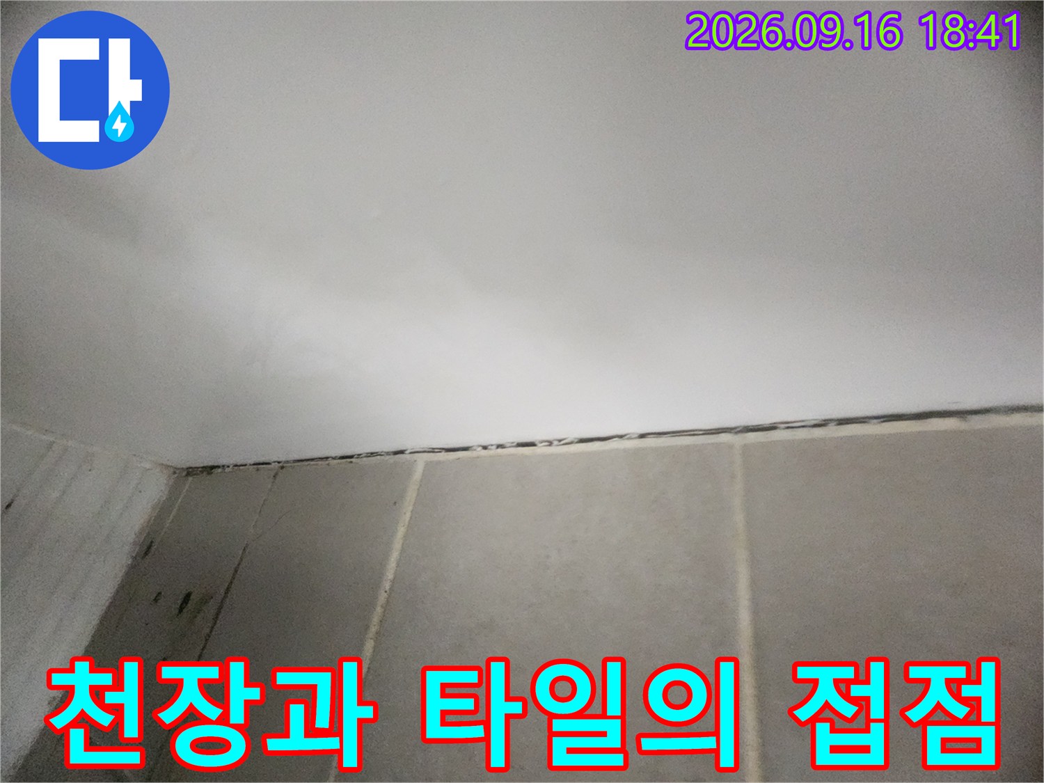 하얀 천장재와 베이지색 타일이 맞닿은 상단 경계 부위입니다.