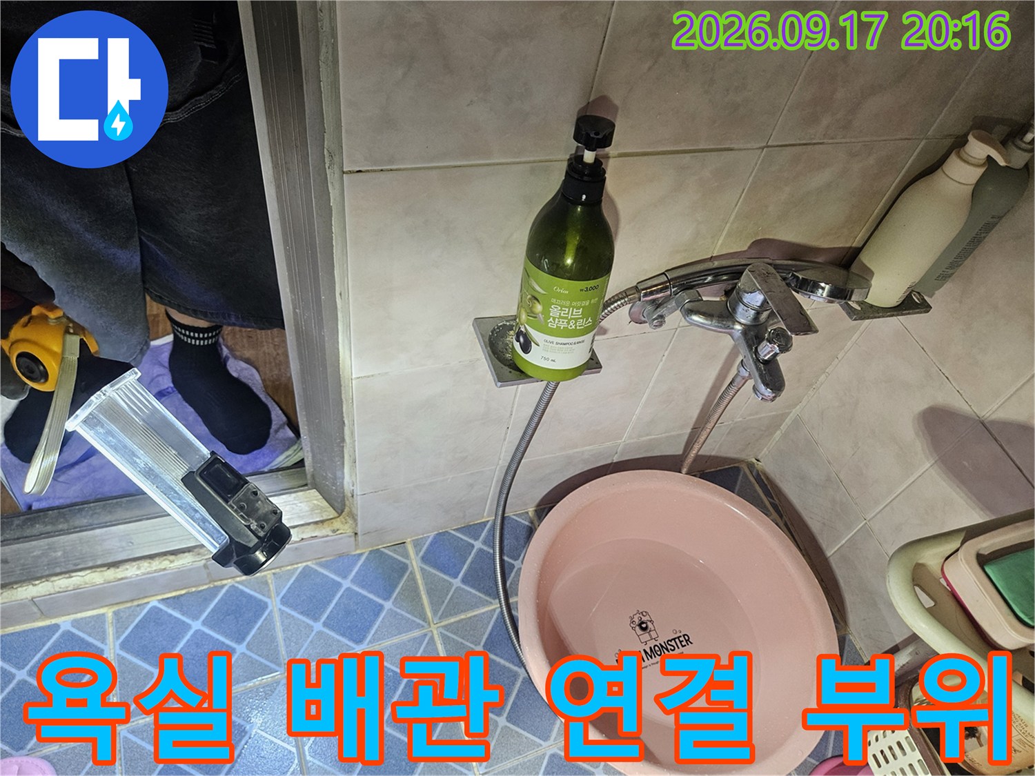 벽면 수전 아래쪽의 금속 배관과 호스 연결부를 촬영한 이미지입니다.