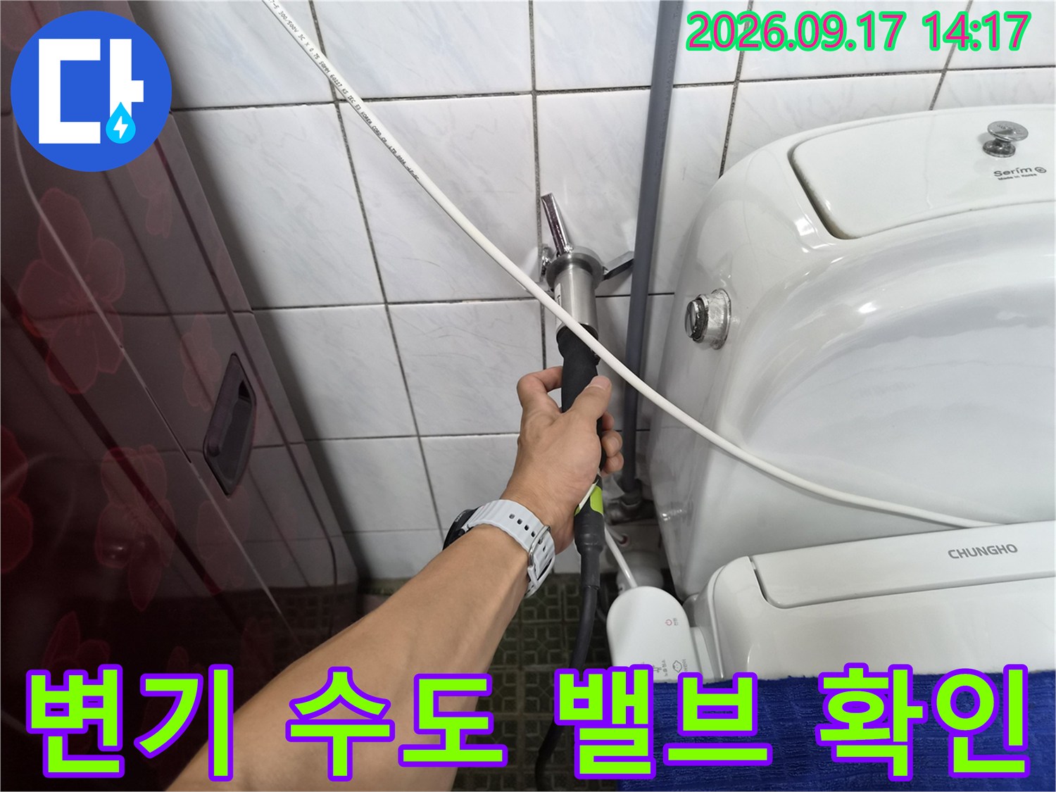 벽면 타일에 설치된 변기 급수 밸브와 연결 호스를 점검하는 손