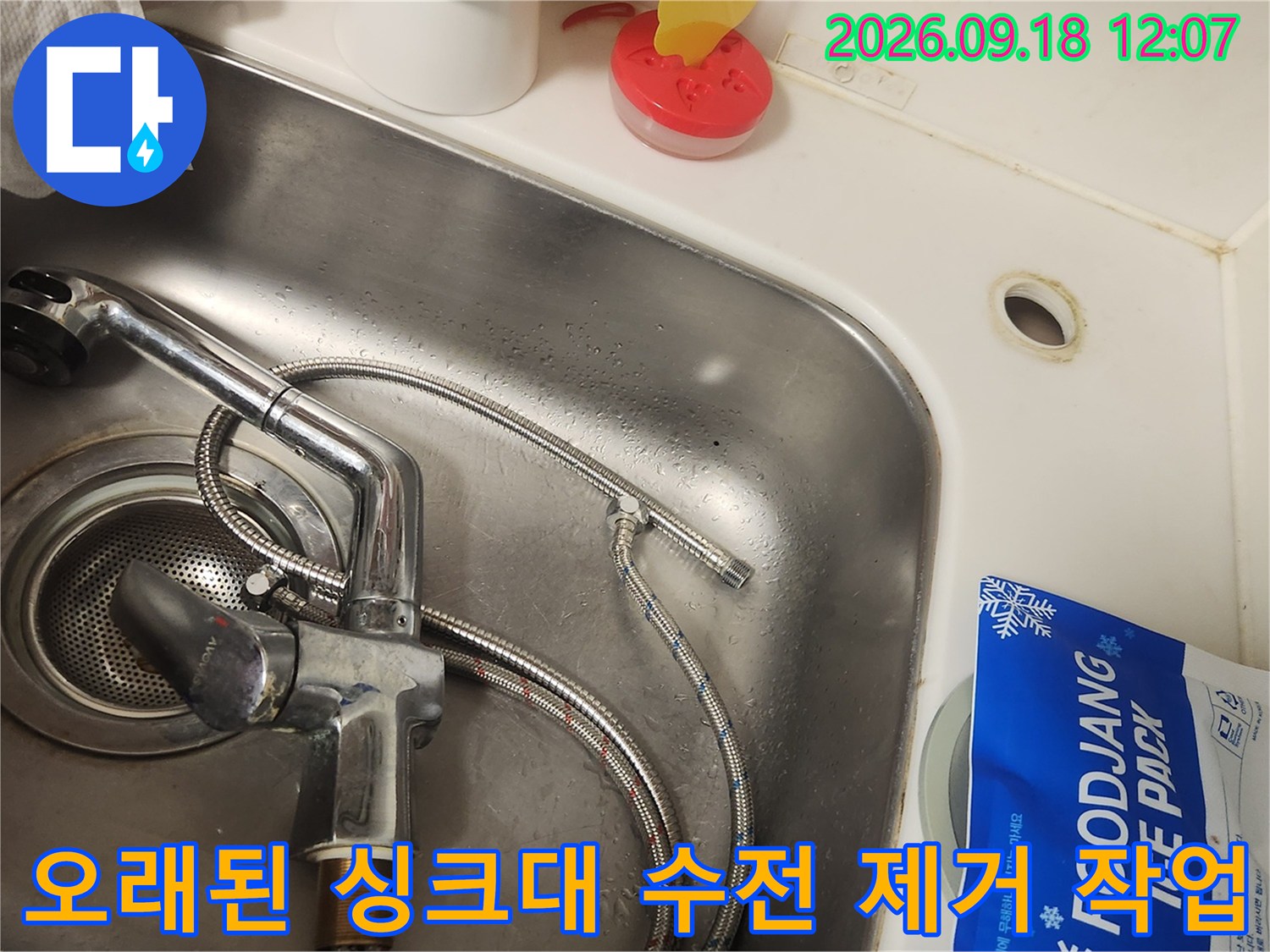 스테인리스 싱크볼 내부에 설치되어 있는 노후된 주방 수전의 모습입니다.