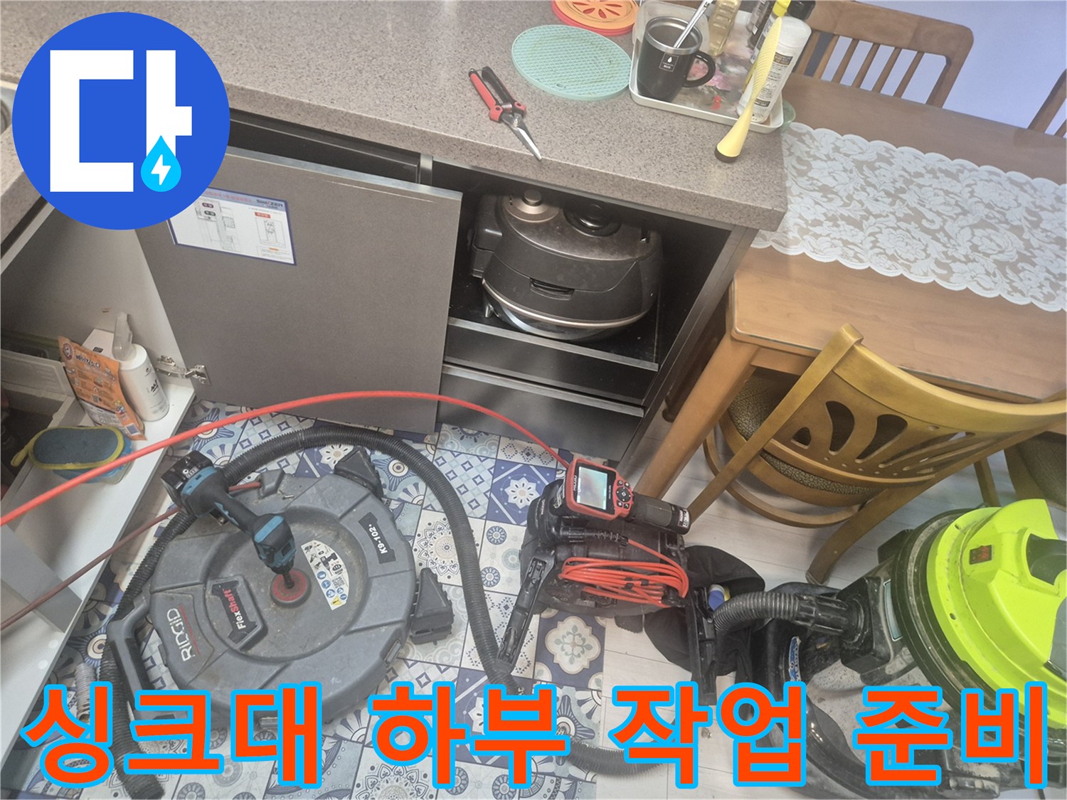 주방 싱크대 하부장 아래에 배치된 배관 점검용 전문 장비들