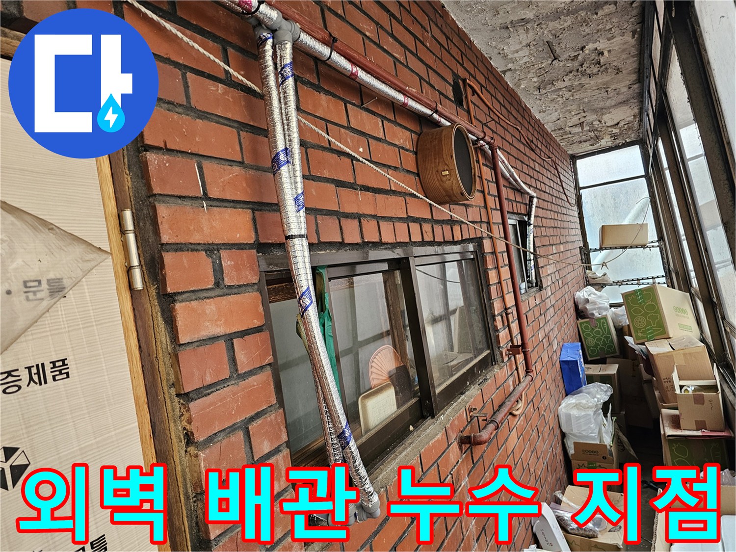 붉은 벽돌 외벽-임시 연결 호스와 노후된 배관의 복잡한 모습